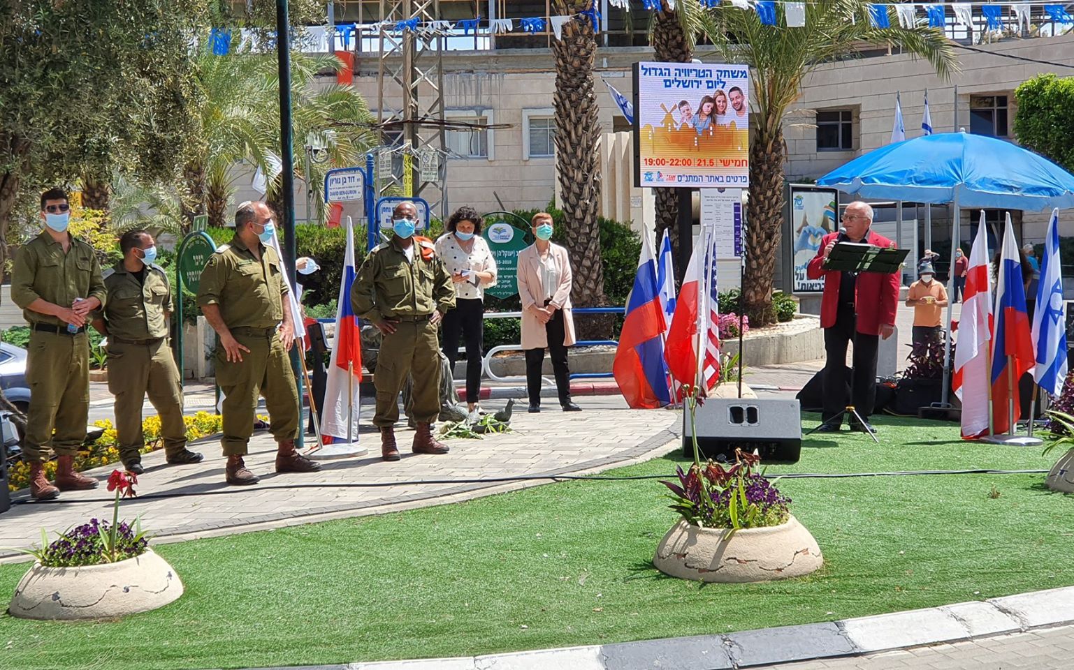 תמונה של אנשים עוטי מסכות מיגון נגד קורונה בטקס בגינה ציבורית