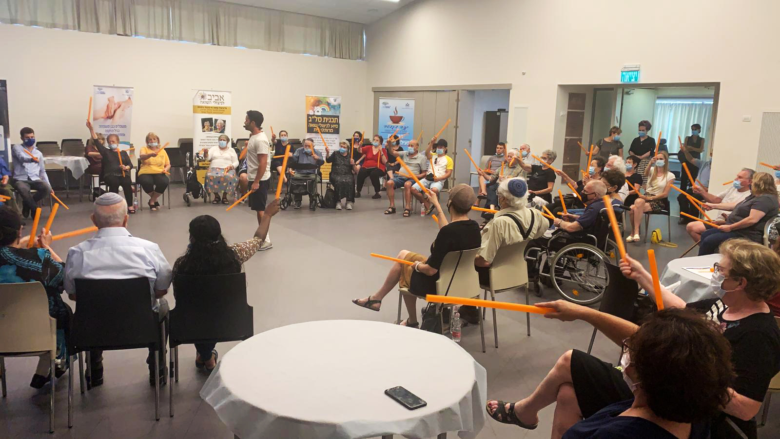 צילום של קבוצת גמלאים ישובים על כיסאות גלגלים וכיסאות רגילים 