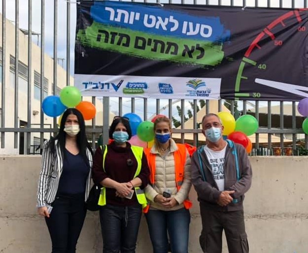 הורים לובשי וסט זהירות ועוטים מסכות מצולמים על רקע חצר בית ספר
