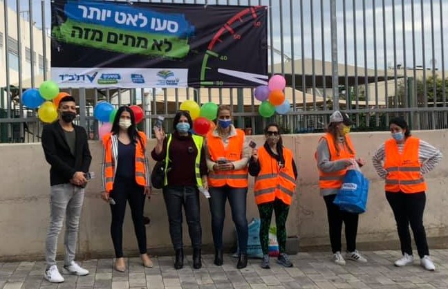 הורים לובשי וסט זהירות ועוטים מסכות מצולמים על רקע חצר בית ספר